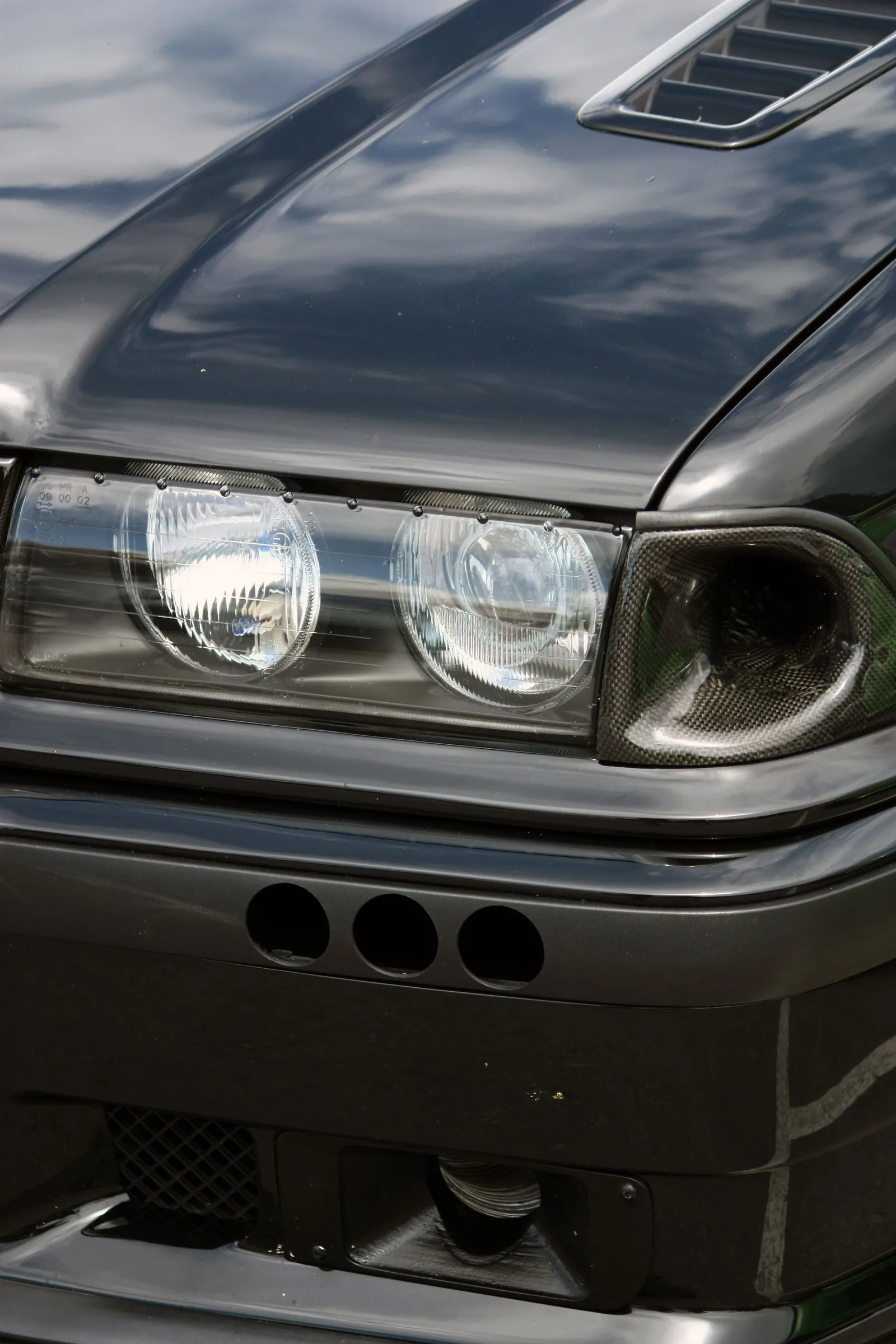 Polierte Front eines schwarzen Youngtimers mit Doppelscheinwerfern